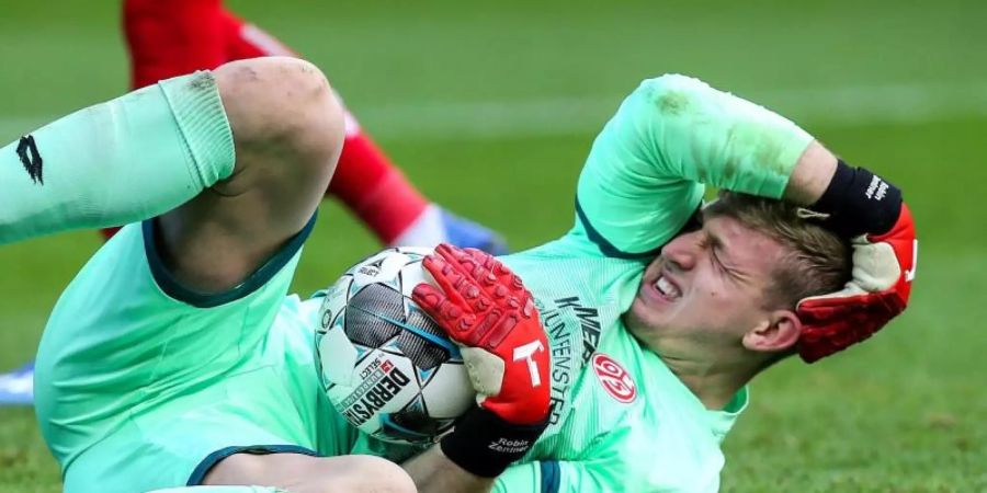 Torwart Robin Zentner von Mainz 05 hält sich nach einem Zusammenstoss den Kopf. Foto: Andreas Gora/dpa
