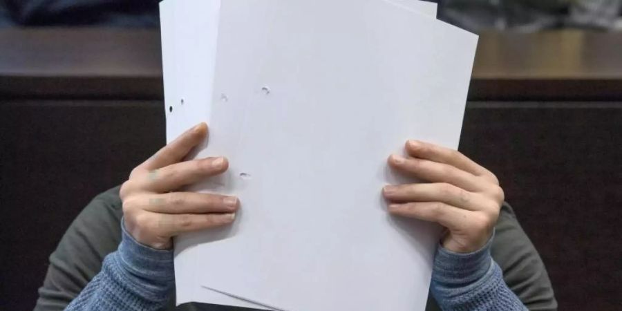 Mit Zetteln verdeckt Ali B. beim Betreten des Gerichtssaals sein Gesicht vor den Kameras der Journalisten. Foto: Boris Roessler