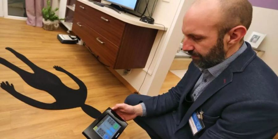 Alexander Karl, Laboringenieur der Fachhochschule Kempten, testet in einer Forschungswohnung ein digitales Steuerelement. Der Fussboden ist mit Sturzsensoren ausgestattet. Foto: Karl-Josef Hildenbrand