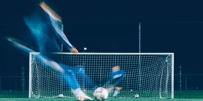 Fussballspieler und Tormann spielen vor dem Tor Fussballspieler