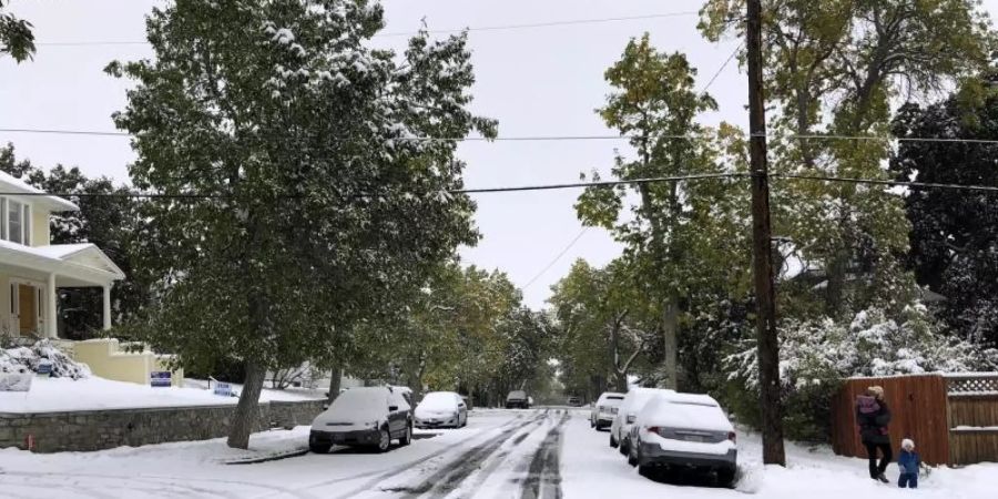 Fussgänger auf einem schneebedeckten Fussweg. Ein Schneesturm hat Teile des US-Bundesstaats Montana lahmgelegt. Foto:  Matt Volz/AP