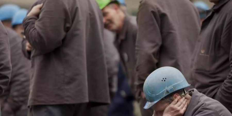 Nachdenklich: Arbeiter auf einem Werftgelände zwischen seinen Kollegen. Der Deutsche Industrie- und Handelskammertag sieht die Konjunktur auf Talfahrt. Foto: Arno Burgi/dpa-Zentralbild/dpa