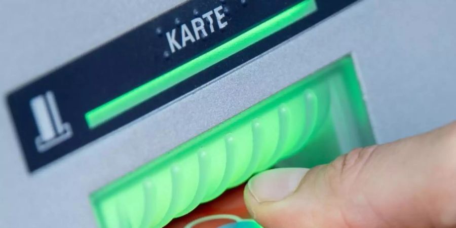Eine Bankkundin steckt ihre Girokarte in einen Geldautomaten. Foto: Fabian Sommer/dpa/Illustration