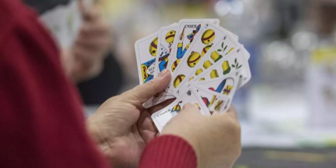 Eine Frau begutachtet das Blatt in ihrer Hand. Jass