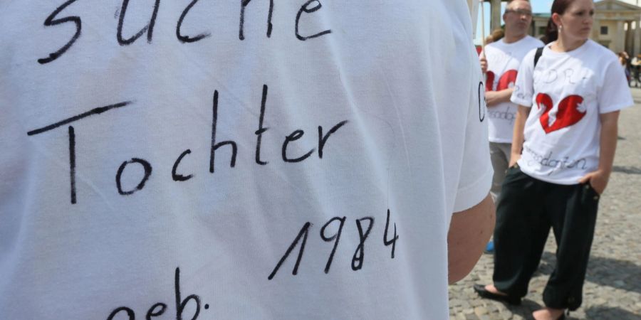 "Suche Tochter, geb. 1984" steht auf dem T-Shirt einer Frau bei einer Kundgebung.