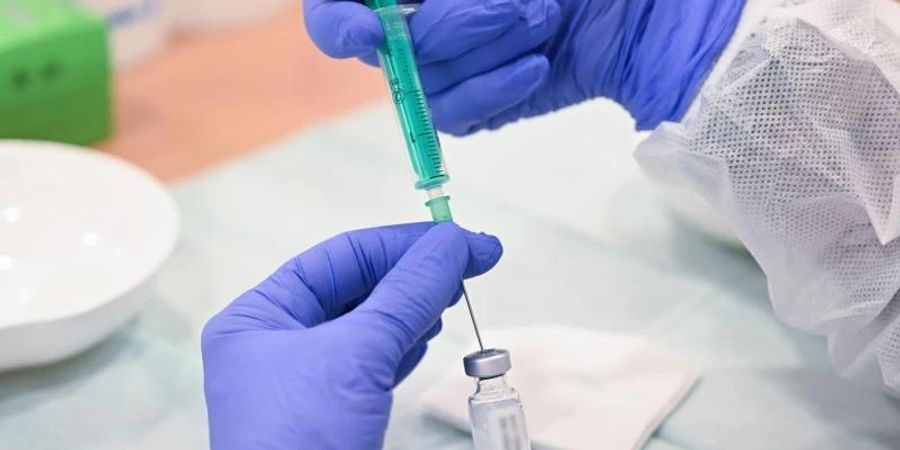 Eine Mitarbeiterin des Klinikums Stuttgart bereitet eine Spritze für eine Impfung gegen das Coronavirus vor. Foto: Bernd Weissbrod/dpa