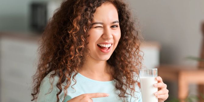 Frau zeigt auf Milchglas