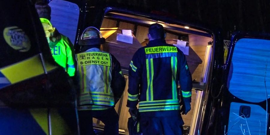Einsatzkräfte stehen vor einem verunglückten Leichenwagen.