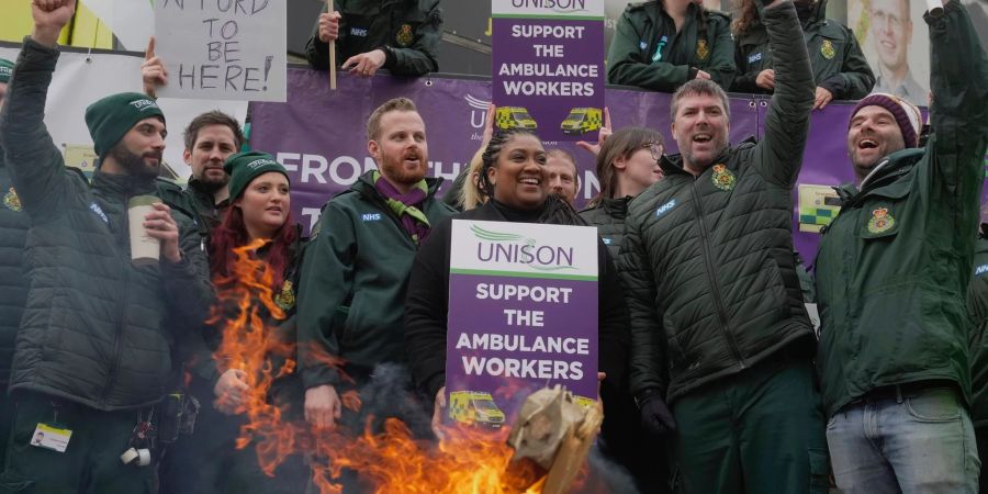 Mitarbeiter des Rettungsdienstes stehen während eines Streiks vor einem Feuer in London.