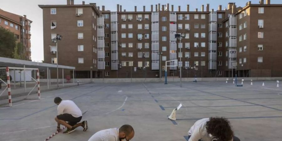 Lehrer machen mit Klebeband Markierungen auf einem Schulhof in Madrid, um den Sicherheitsabstand zwischen den Schülern zu gewährleisten. Foto: Bernat Armangue/AP/dpa