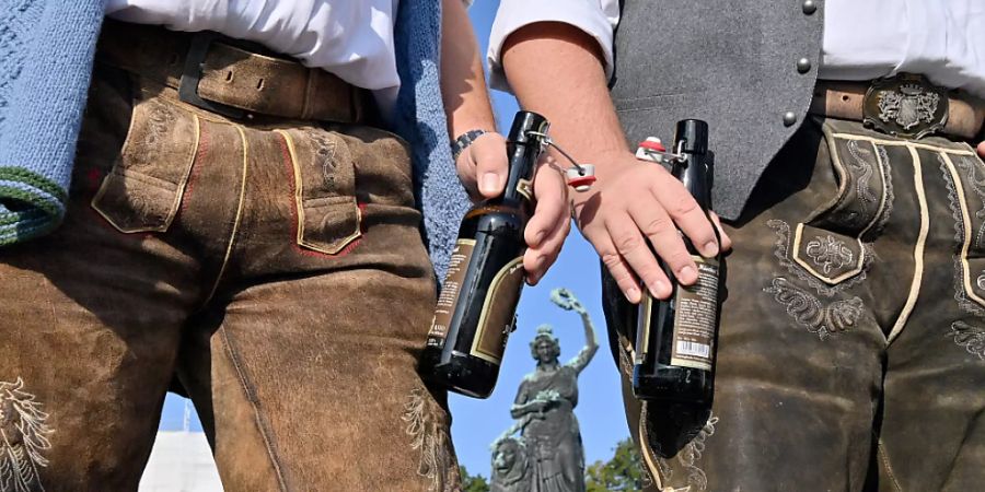 dpatopbilder - Zwei Männer in Tracht stehen mit Bierflaschen auf dem Wiesn-Gelände in München. Foto: Peter Kneffel/dpa