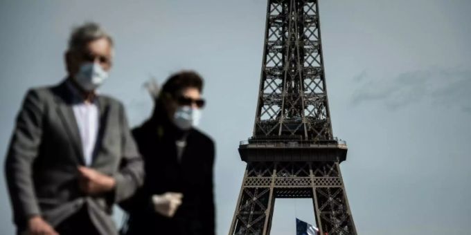 Ein Paar mit Schutzmasken vor dem Eiffelturm. Coronavirus