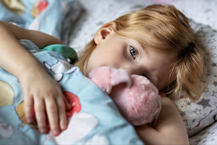 Junges Mädchen mit Kuscheltier im Bett