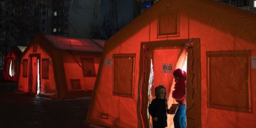 dpatopbilder - Menschen stehen im Eingangsbereich eines Zeltes, das in einem Wohnviertel aufgestellt wurde und in dem sie sich aufwärmen können, nachdem russische Luftangriffe wiederh...
