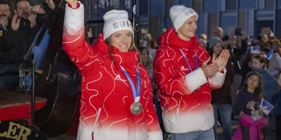 Nadine Fähndrich (links) und Gregor Deschwanden mit ihren Olympia-Medaillen beim Einzug in die Mehrzweckhalle von Horw, wo sie dem örtlichen Skiclub angehören.