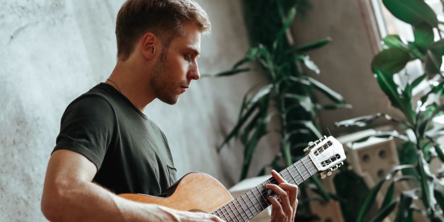 Mann spielt Gitarre im Zimmer, Pflanzen