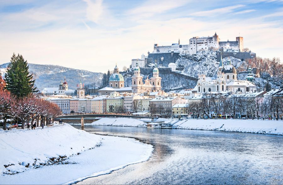 Verschneites Salzburg: Blick auf die schneebedeckte Festung Hohensalzburg und den Fluss Salzach.