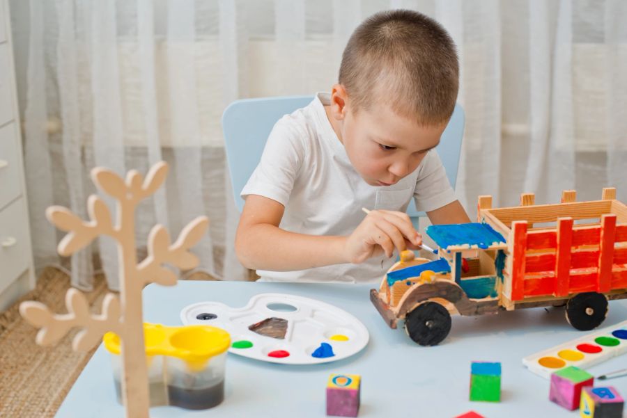 Junge malt Holzspielzeug an