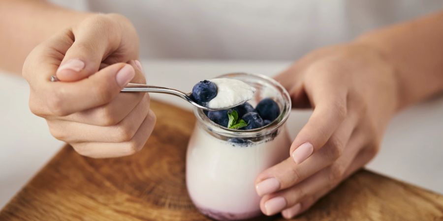 Frauenhände Löffel Joghurt Heidelbeeren