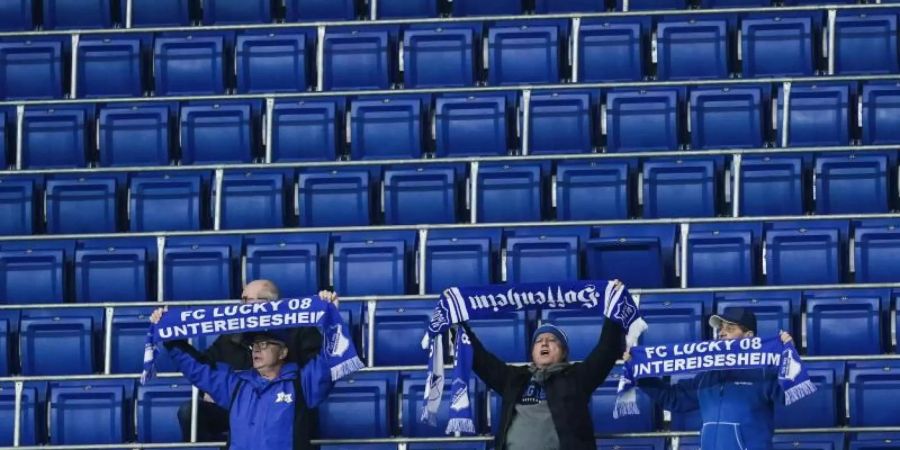 Die Zugangsregeln bei der TSG 1899 Hoffenheim werden weiter verschärft: Fans halten vor leeren Zuschauerrängen ihre Schals in die Höhe. Foto: Uwe Anspach/dpa