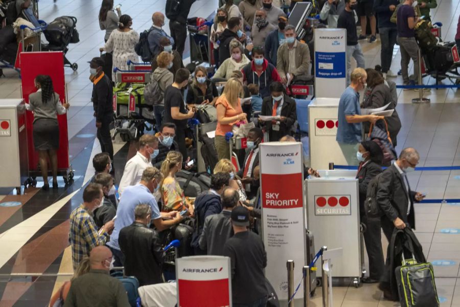 Reisende stehen am Flughafen in Johannesburg in der Schlange. Der Flughafen liegt in der Provinz, in der die Omikron-Variante des Coronavirus in Südafrika zuerst bemerkt worden ist.