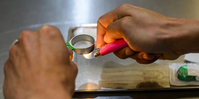Eine Person bereitet in einem Konsumraum für Drogensüchtige eine Drogendosis vor.