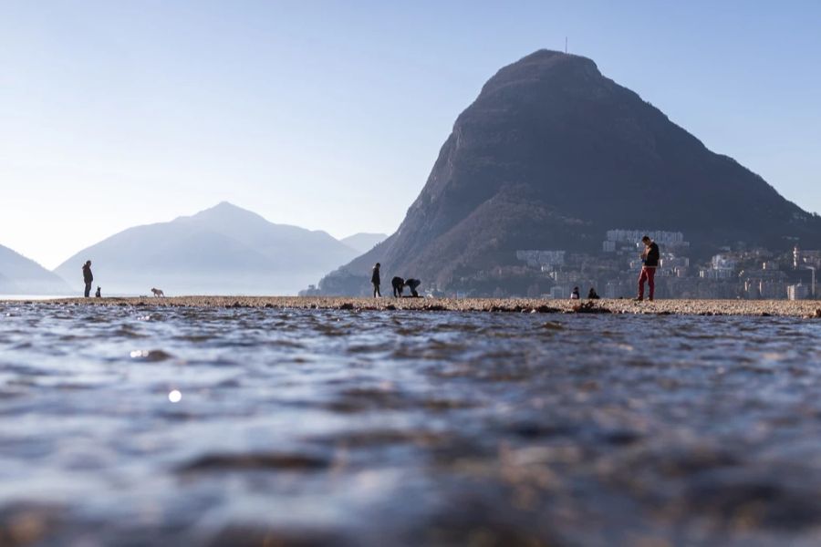 Menschen verweilen am Luganersee mit tiefem Wasserstand, aufgenommen am Mittwoch, 9. Februar 2022, in Lugano TI. Das trockene Wetter wirkt sich auf die Pegelstände aus.