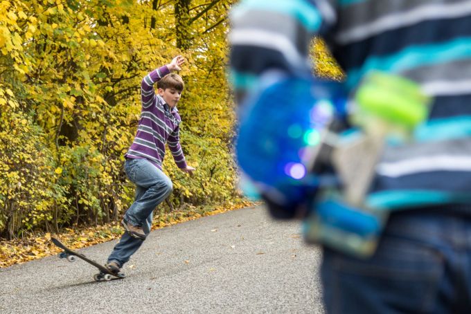In einem bestimmten Alter sind Kinder noch nicht vollständig in der Lage, ihren Körper zu stabilisieren. Das steigert das Verletzungsrisiko. Kind Skateboard Strasse Junge