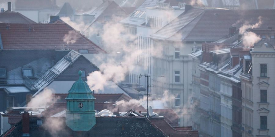 Rauch strömt aus Kaminen auf Dächern von Mehrfamilienhäuser.