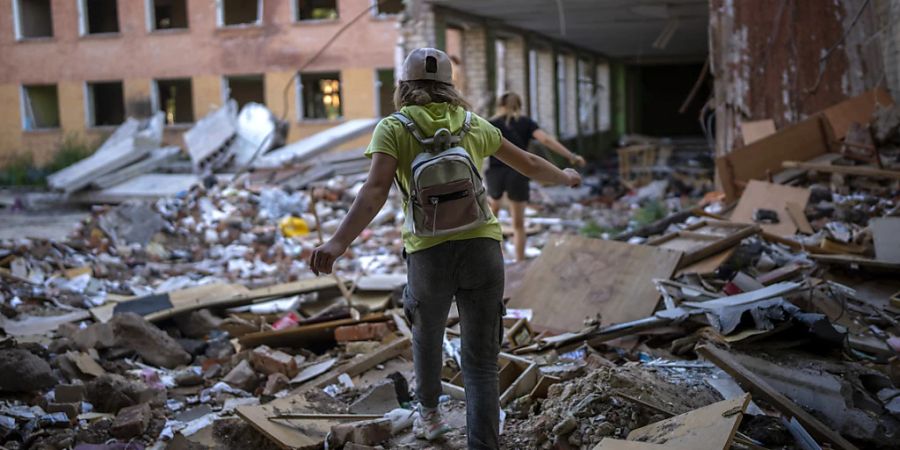 ARCHIV - Die Schülerin Karina Muzyka geht auf den Trümmern der Tschernihiwer Schule Nr. 21, die am 3. März von russischen Streitkräften bombardiert wurde. Foto: Emilio Morenatti/AP/dpa