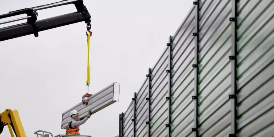 Bauarbeiter errichten einen Lärmschutz. Foto: Britta Pedersen/dpa-Zentralbild/dpa
