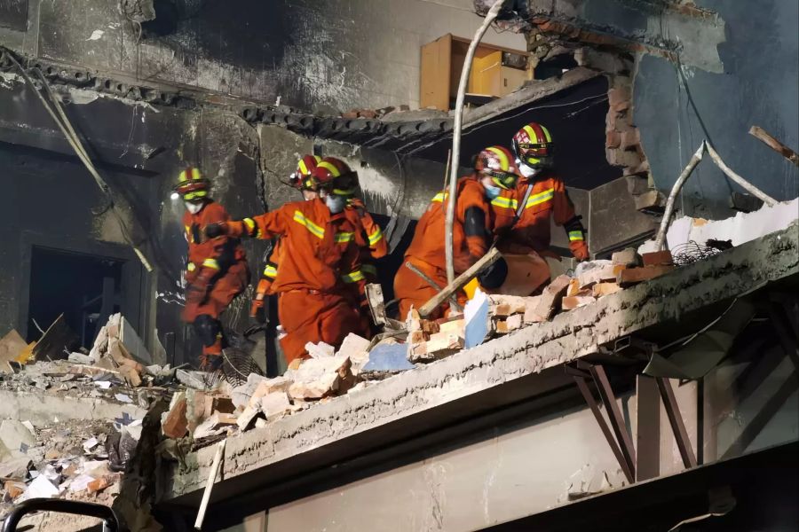 Feuerwehrleute suchen nach Opfern in einem beschädigten Gebäude nach der Explosion eines Tanklastwagens.