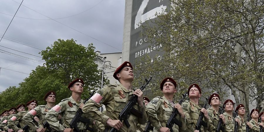 dpatopbilder - ARCHIV - Der Buchstabe «Z» ist auf einem Gebäude, unter dem Soldaten der russischen Nationalgarde (Rosguardia) in der von Russland 2014 annektierten Stadt zu sehen entlangmarschieren. Foto: Uncredited/AP/dpa/Archiv