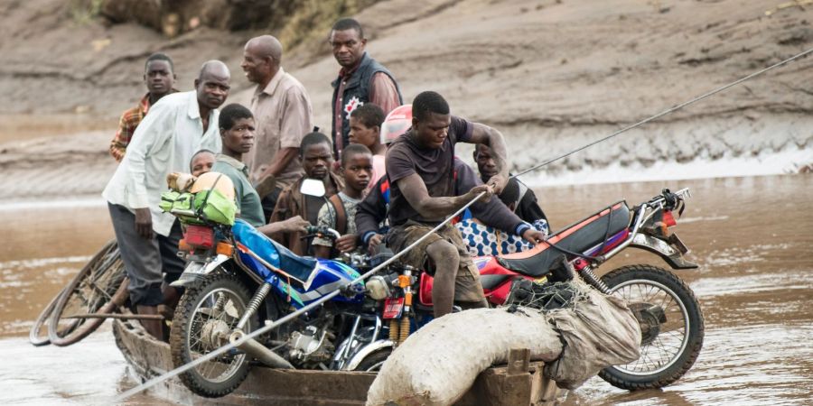 Männer transportieren in Malawi ihre geretteten Habseligkeiten mit einem Holzboot.