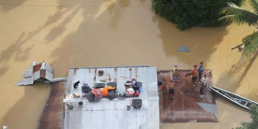 Menschen stehen auf dem Dach eines überfluteten Hauses bei Cagayan auf den Philippinen. Foto: Uncredited/Philippine Coast Guard/AP/dpa