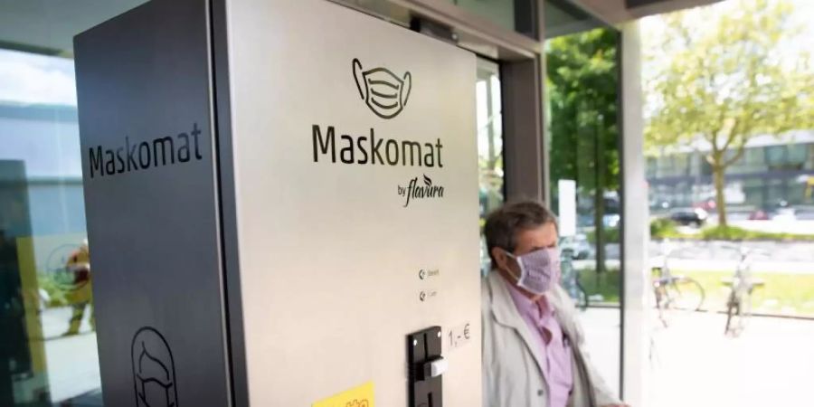 Ein «Maskomat» des Berliner Automatenherstellers Flavura steht am Eingang eines Supermarktes. Foto: Christian Charisius/dpa