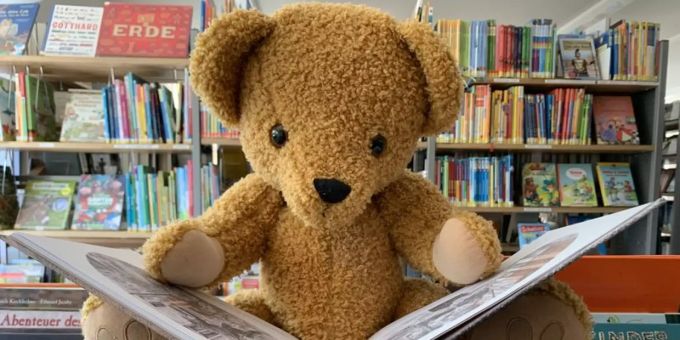 Bär liest ein Kinderbuch.