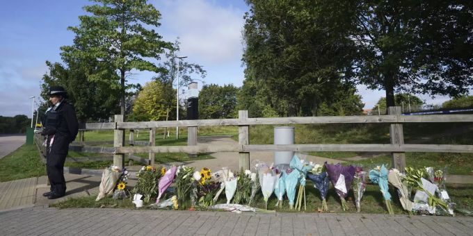 Ein Polizeibeamter steht neben Blumengebinden im Cator Park in Kidbrooke, in der Nähe der Stelle, an der die Leiche von Sabina Nessa gefunden wurde, in London, Donnerstag, 23. September 2021. Britain Woman Killed
