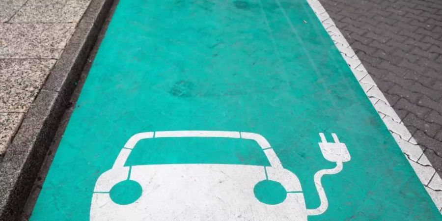 Ein stilisiertes Auto auf grünen Grund markiert einen Parkplatz mit Ladesäule für Elektrofahrzeuge. Foto: Jan Woitas/zb/dpa