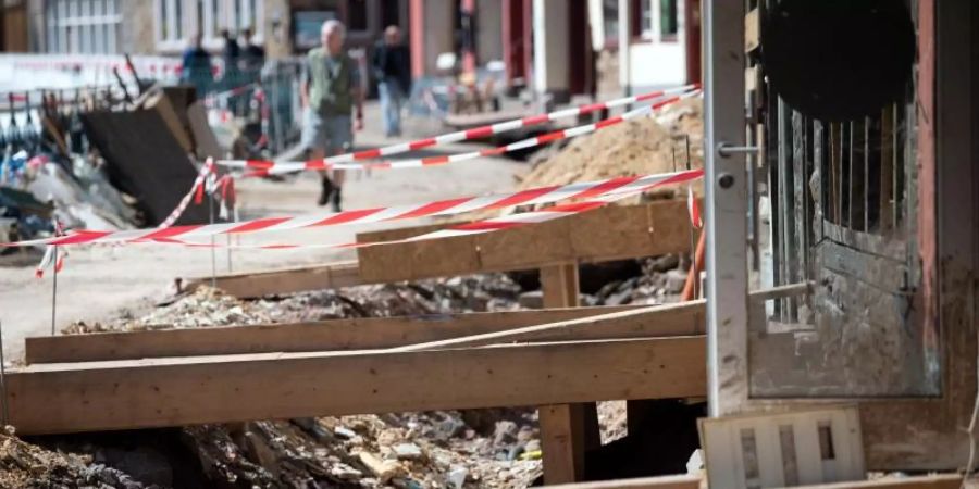 Mit Holzbrücken gelangen Anwohner in der zerstörten Altstadt von Bad Münstereifel in ihre Häuser. Die Flutkatastrophe Mitte Juli hat bislang Versicherungsschäden von rund sieben Milliarden Euro verursacht und damit mehr als bisher erwartet. Foto: Federico Gambarini/dpa