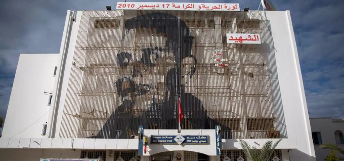 Auf der Fassade eines Postamtes in der tunesischen Kleinstadt Sidi Bouzid ist das Gesicht des tunesischen Gemüsehändlers Mohammed Bouazizi abgebildet, der sich am 17. Dezember 2010 selbst anzündete. Zehn Jahre Arabische Aufstände