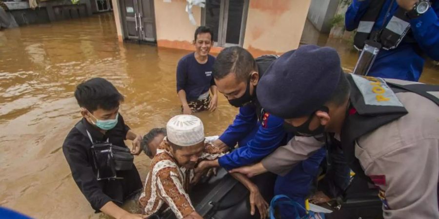 Rettungskräfte helfen einem älteren Mann in einem überfluteten Dorf in ihr Boot. Foto: Putra/AP/dpa