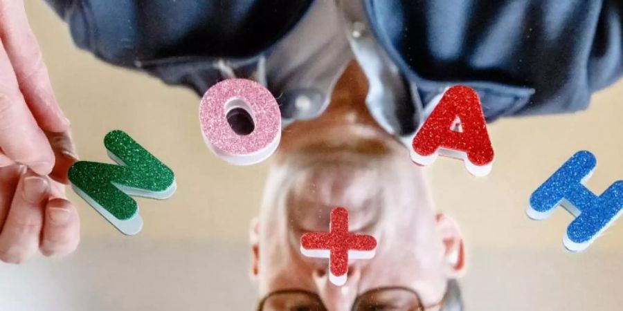 Der Vornamen-Experte Knud Bielefeld legt mit Buchstaben die beliebtesten Vornamen des Jahres 2020, Mia und Noah, auf einem Spiegel. Foto: Markus Scholz/dpa