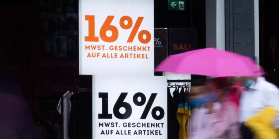 Mit Schildern mit der Aufschrift «16% Mehrwertsteuer geschenkt auf alle Artikel» wirbt ein Geschäft in der Hamburger Innenstadt. Foto: Christian Charisius/dpa