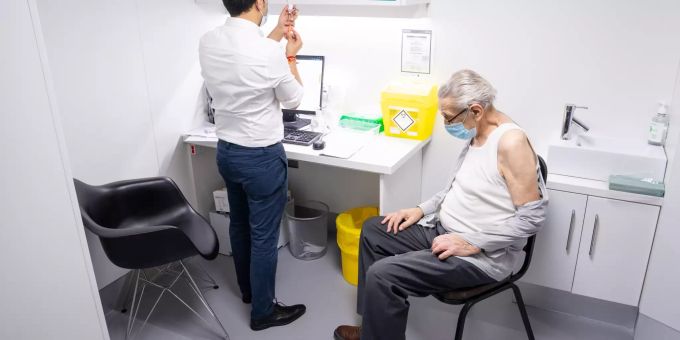 Ein Mann lässt sich in einer Apotheke gegen das Corona-Virus impfen. 80 jährige