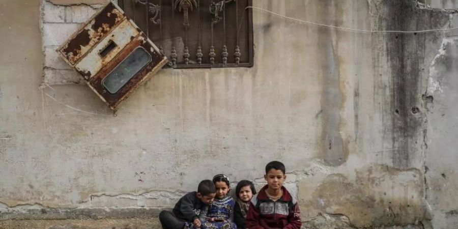 Syrische Kinder sitzen zwischen beschädigten Gebäuden im Dorf Afes. Rund zehn Jahre nach dem Beginn des Syrien-Konfliktes beklagt der UN-Menschenrechtsrat schwere Kriegsverbrechen in dem Krisenland. Foto: Anas Alkharboutli/dpa