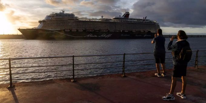Zwei Personen schiessen ein Foto des Kreuzfahrtschiff Mein Schiff 2 im Hafen von Santa Cruz. Cruiseliner Mein Schiff 2