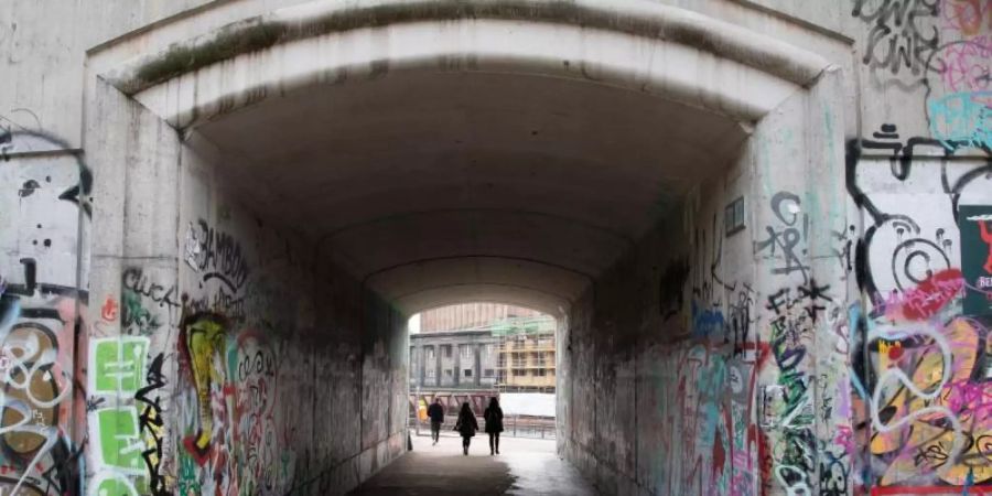 Menschen gehen durch die Unterführung zum Monbijoupark in Berlin-Mitte, in der Unbekannte eine Rose und eine Kerze abgelegt haben. Der 13-Jährige war hier bei einem Streit tödlich verletzt worden. Foto: Paul Zinken/dpa