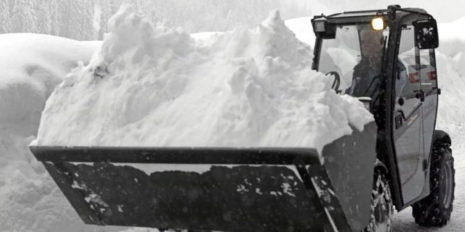 Ein Bagger befreit eine Strasse in Niedertauern vom Schnee.