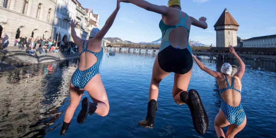 Bereits am Nachmittag sprangen rund 40 Rettungsschwimmer und Schwimmerinnen der Schweizerischen Lebensrettungs-Gesellschaft SLRG Sektion Luzern zusammen an Silvester in die Reuss in der Altstadt von Luzern mit der Kapellbrücke in Hintergrund.